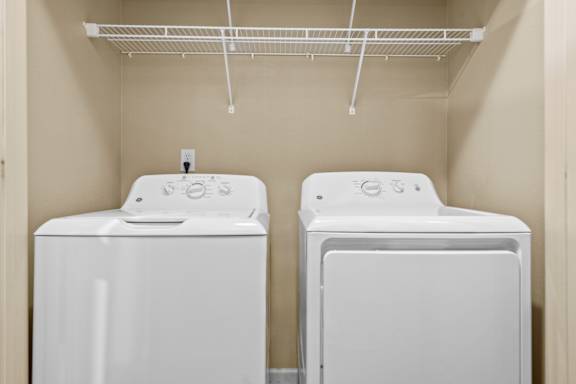 Two white front loading washing machines in a small laundry room.