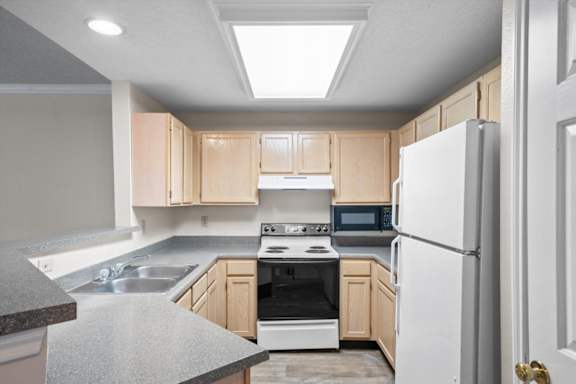 A kitchen with a white refrigerator, sink, and stove.at The Claremont Apartment Homes, Overland Park Kansas