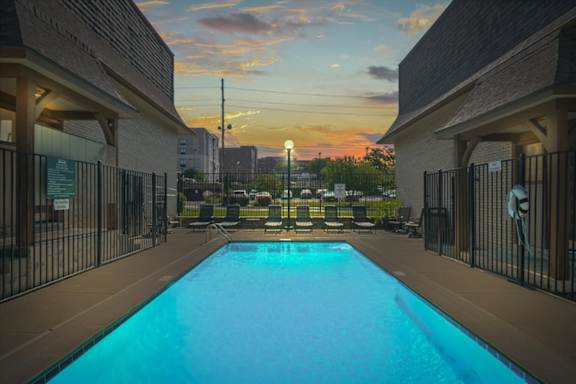 A swimming pool surrounded by a fence and buildings. at Malvern Hill Apartment Homes, Kansas