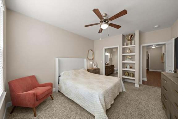 A bedroom with a bed, chair, and shelves.