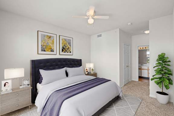 A bedroom with a ceiling fan and an attached bathroom.