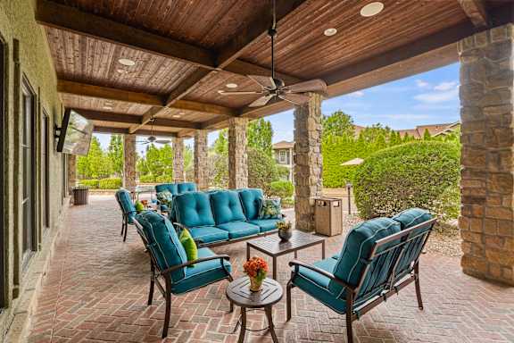 A patio with blue chairs and a table with a flower vase on it.