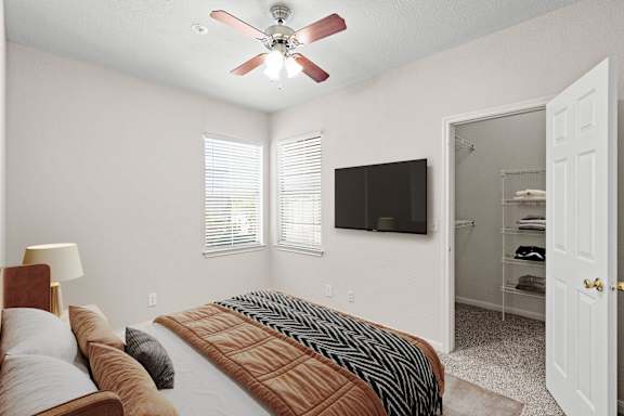 A bedroom with a ceiling fan and large walk in closet.