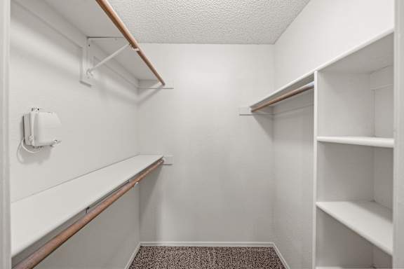 A white closet with shelves and a carpeted floor. at Coventry Oaks Apartments, Overland Park