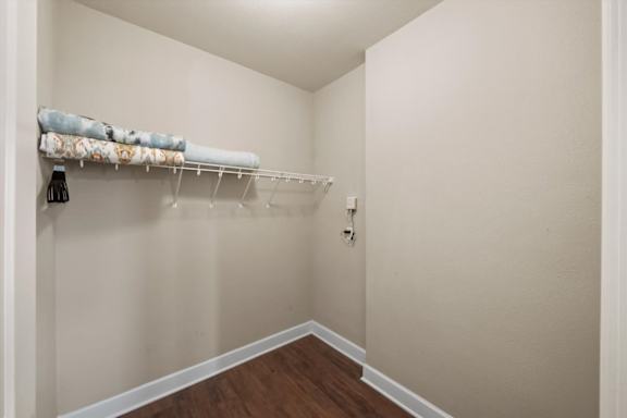 A white closet with a wooden floor and a white shelf.