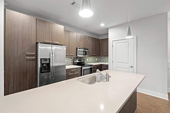 A modern kitchen with a white countertop and stainless steel appliances.
