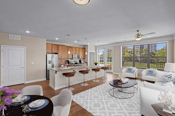 A modern kitchen and dining area with high ceilings and a view of greenery.