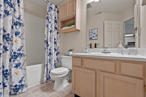 a bathroom with a white toilet next to a bathtub with a blue and white shower curtain at Claremont, Overland Park