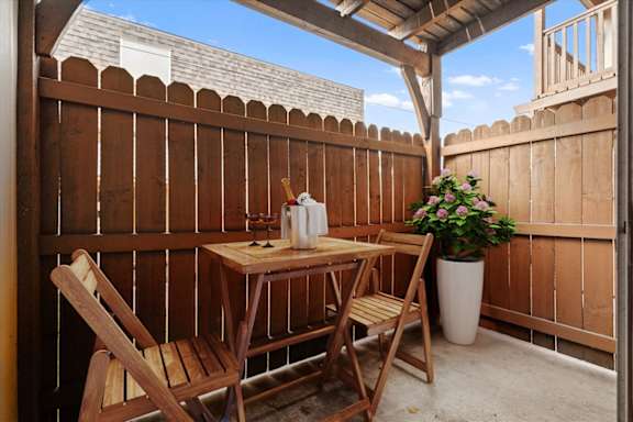 A wooden table with two chairs and a vase of flowers on a patio. at Malvern Hill Apartment Homes, 66103