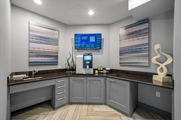 A modern kitchen with a countertop and a digital display on the wall.