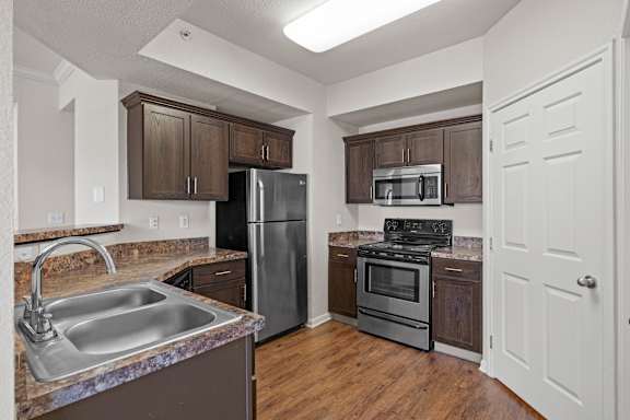 A kitchen with espresso cabinets, stainless steel appliances and a large pantry.