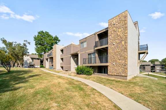 modern apartment building with a stone facade and balconies at Bremerton Park Apartment Homes , Prairie Village