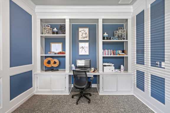 A room with a desk and a chair in front of a wall with shelves. at Crescent Apartment Homes, Lenexa, 66219