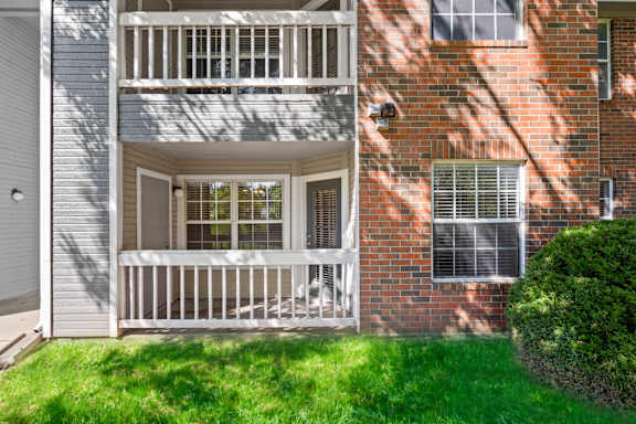 Private, fenced-in patio and balcony on a brick apartment building, overlooking a grassy area at Stonebriar Apartments.