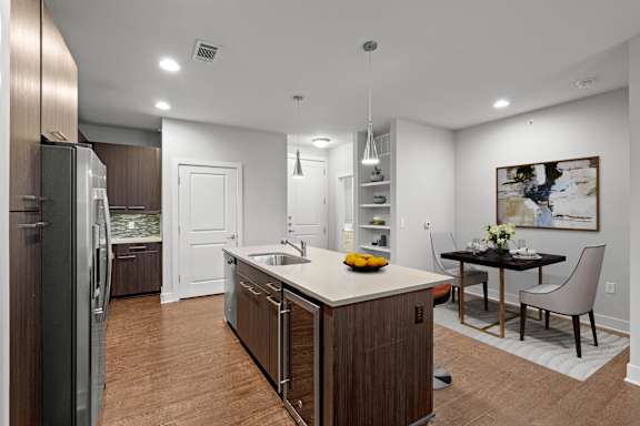 A modern kitchen with a wooden island and a dining table set for two.