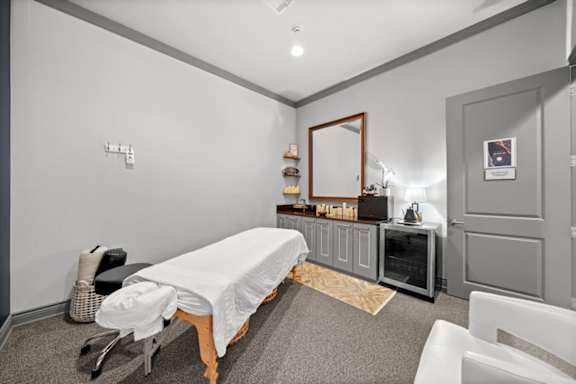 A room with a massage table and a mirror on the wall.