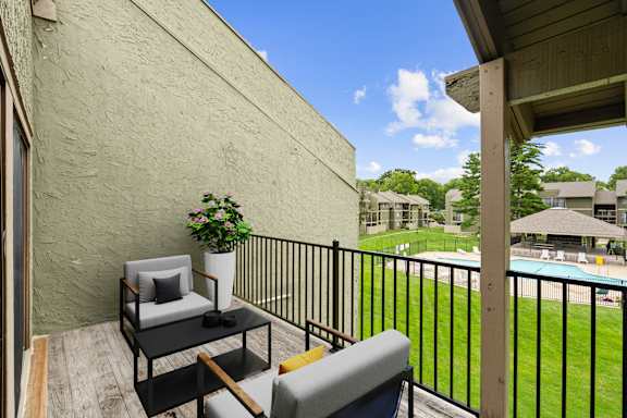 A balcony with a table and chairs overlooking a pool.