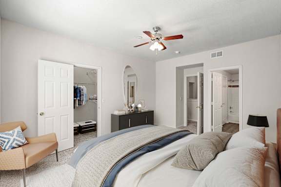 A bedroom with a ceiling fan, large walk in closet and attached master bathroom.