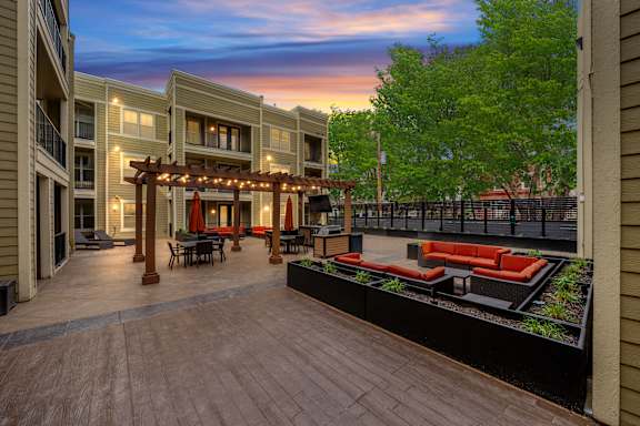 Spacious courtyard at West 39th Street Apartments with multiple seating areas, pergola, and outdoor TV at West 39th Street Apartments, Kansas City, Missouri