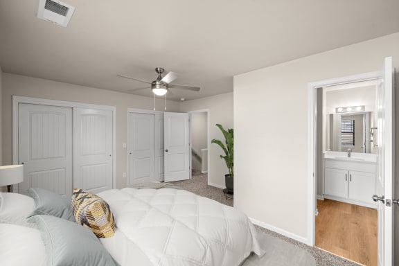 a bedroom with a white bed and a ceiling fan