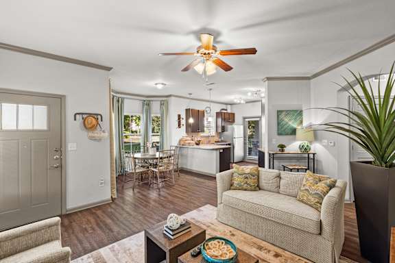 A living room with a couch, a coffee table, and a ceiling fan.