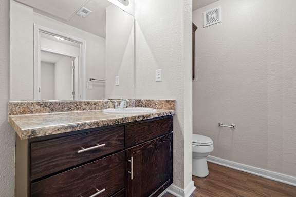 A bathroom with espresso cabinets and a large vanity mirror.