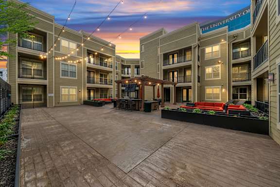 Outdoor common area at West 39th Street Apartments with lounge furniture, string lights, and backdrop  at West 39th Street Apartments, Kansas City