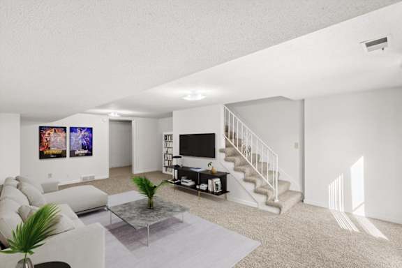 A living room with a staircase and a television.