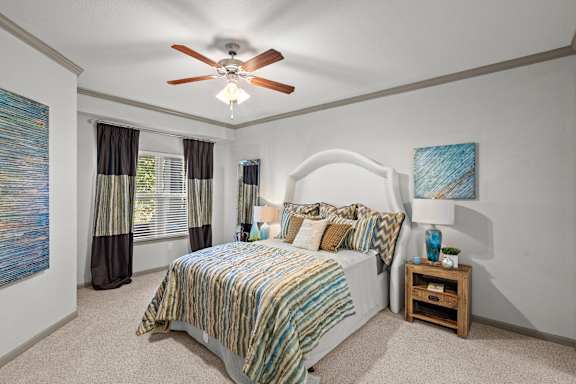 A bedroom with a bed, nightstand, and a ceiling fan.