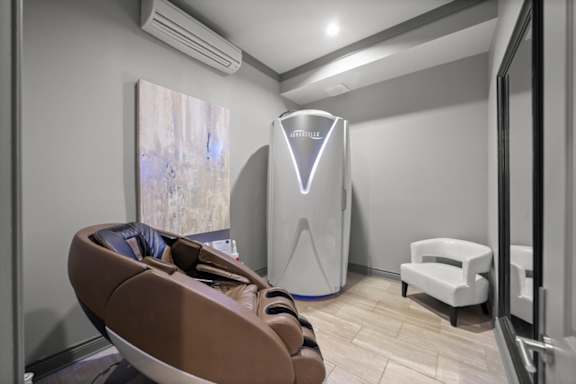 A room with a brown chair and a white cabinet.