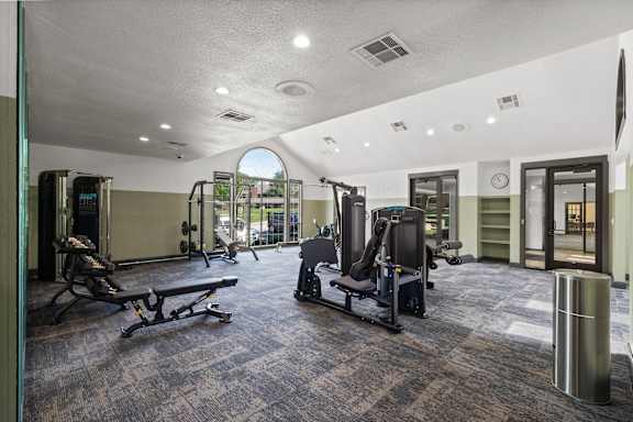 A gym with a variety of equipment including treadmills, weights, and exercise machines.