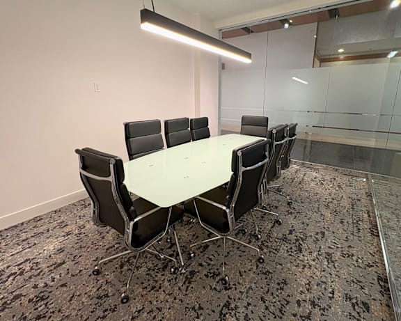 Carpeted meeting room at Sky on Main Apartments with a large table, chairs, and a modern design for professional gatherings.