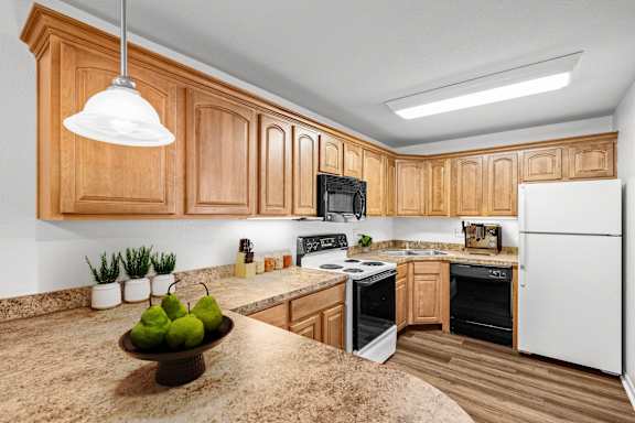A kitchen with granite countertops, upgraded lighting, white appliances, and oak cabinetry.