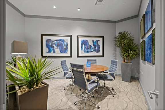 A conference room with a table, chairs, and two framed artworks on the wall.