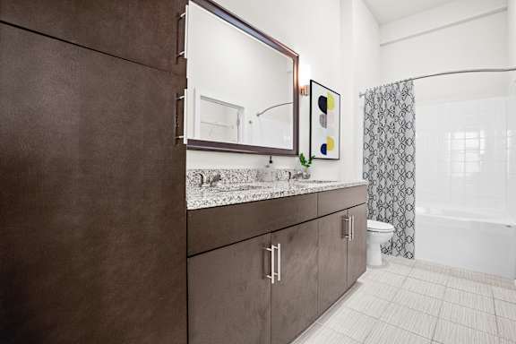 A bathroom with brown cabinets and a marble countertop at West 39th Street Apartments, Missouri, 64111