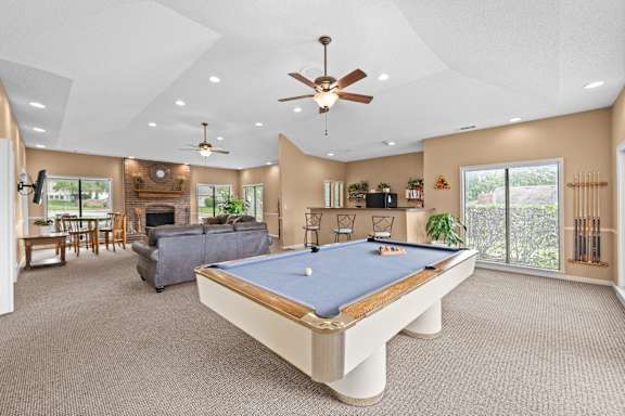 A pool table is in the middle of a room with a ceiling fan. at Coventry Oaks Apartments, Overland Park, KS