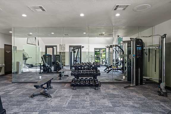 A gym with a variety of equipment including treadmills, weights, and exercise machines.