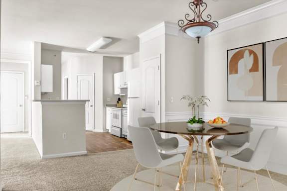 A dining room with a table set for two and a chandelier hanging from the ceiling. at Wynnewood Farms Apartments, Overland Park