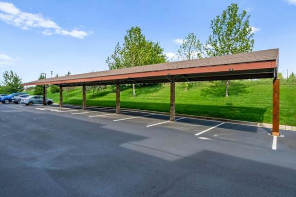 Parking lot with a long covered parking area at The Residences at Bluhawk Apartments, Overland Park, 66085