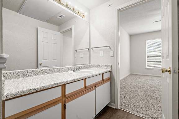A bathroom with a large vanity mirror and lots of storage space under the sink.