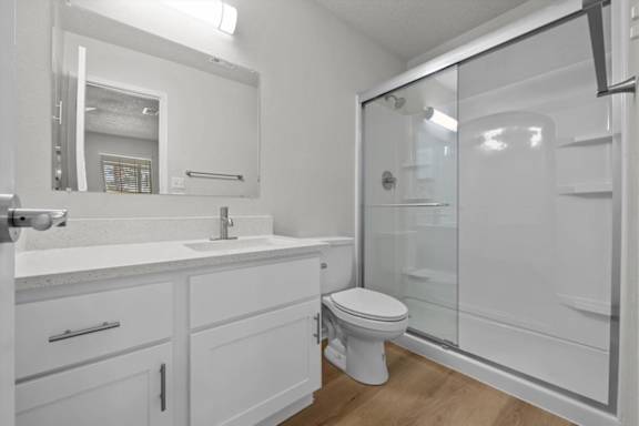 A white bathroom with a toilet, sink, and mirror.
