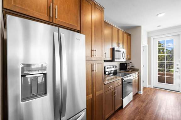 a kitchen with wooden cabinets and stainless steel appliances at The Dorset, Kansas City, Missouri