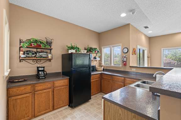 A kitchen with a black refrigerator and wooden cabinets. at Coventry Oaks Apartments, Overland Park, Kansas