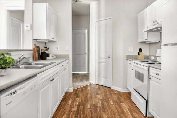 A white kitchen with wood floors and white appliances at Wynnewood Farms Apartments, Overland Park, KS, 66209