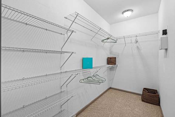 A walk-in closet with white shelving and a brown basket on the floor.