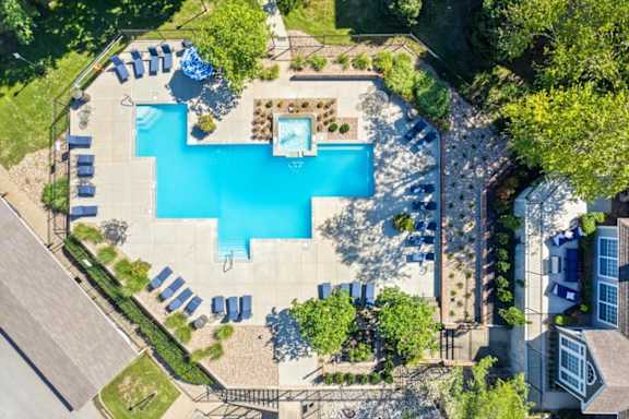 An aerial view of a swimming pool surrounded by trees and lawn chairs.