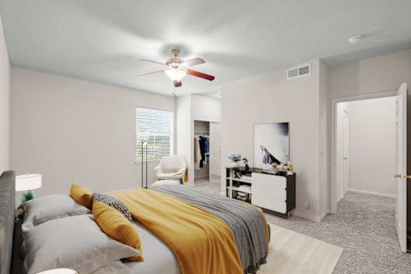 A bedroom with a ceiling fan, window and attached master bathroom.