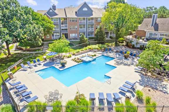 A large swimming pool surrounded by lounge chairs and trees.