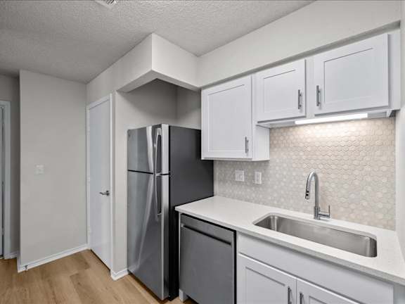 a kitchen with white cabinets and a stainless steel refrigerator