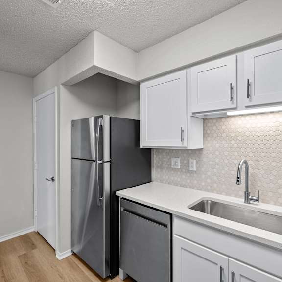 A kitchen with a white fridge and a black dishwasher.